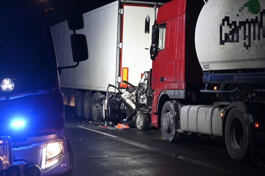 Zdjęcie przedstawia Auto zmiażdżone między dwoma tirami. W środku 3-letnie dziecko